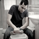 A man in striped t-shirt and jeans uses the Kleva Range "Kleva Clean Sneaks Automatic Shoe Cleaner" to refresh his sneaker over a plastic basin in a bathroom, surrounded by a sink, tiled walls, and bathroom essentials.