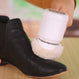 A person uses the Kleva Clean Sneaks Automatic Shoe Cleaner by Kleva Range with a white brush to clean or shine a black textured leather shoe on a light wooden surface.