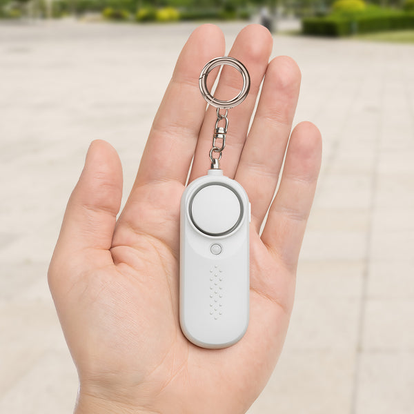 White personal safety alarm shown in hand outdoors