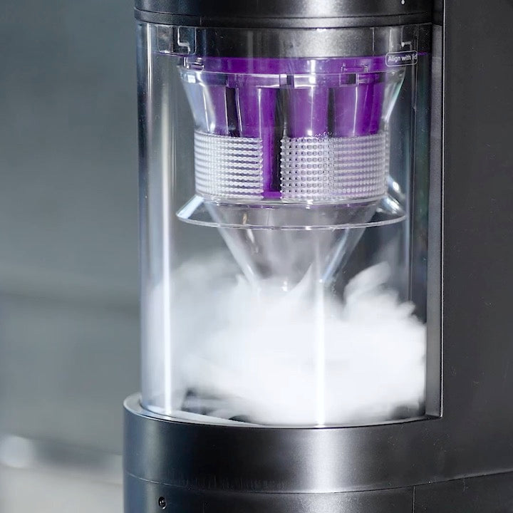 Close-up of the Robo VacIQ's dock: dust swirls into the clear bin as the dock empties the robot.