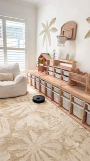 The robot cleaning a big patterned rug in a child's playroom.