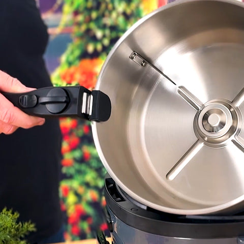 Lifting the uncoated stainless steel pot out of the Spin Crisp by its detachable handle.