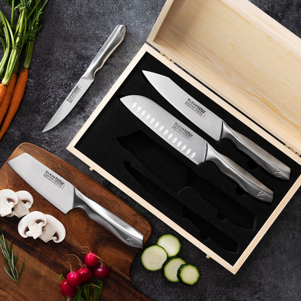 The KlevaCut® LIMITED EDITION 4 Piece Premium Knife Set With BONUS Bamboo Case by Kleva Range lies open on the counter, while its precision knife rests on a wooden cutting board with sliced mushrooms, cucumbers, radishes, and carrots.