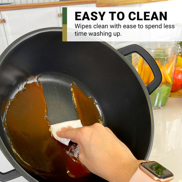 A hand wipes the inside of a large black Diamond Earth® StackSmart pot by Kleva Range, cleaning off sauce with ease. Text reads: EASY TO CLEAN – Less time washing up. Kitchen items appear in the background. Buy one GET ONE FREE!.
