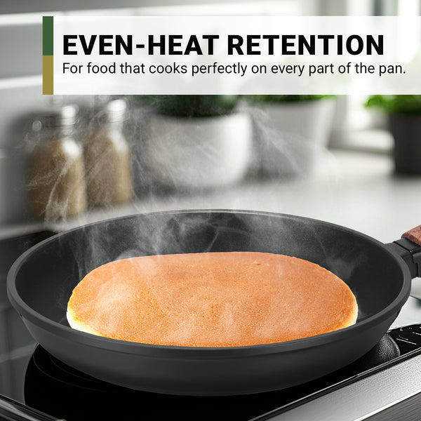A pancake cooks evenly in the black Kleva Range Diamond Earth® StackSmart 6pc Cookware Set with detachable handles. Text: Even-Heat Retention for perfect results. Buy one GET ONE FREE! Kitchen items are blurred in the background.