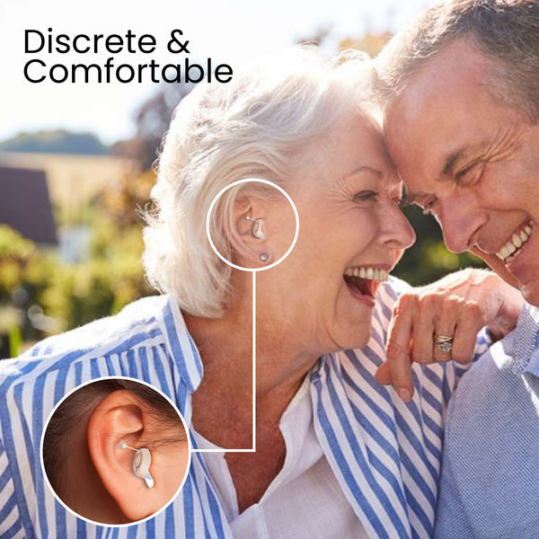 An older couple smiles outdoors. The woman's ear features a highlighted Kleva HearClear Mini Rechargeable Hearing Sound Amplifier from Kleva Range, shown in a close-up. Text in the top left corner reads "Discrete & Comfortable.