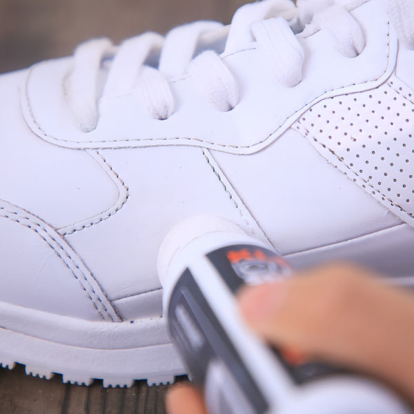 A hand uses the Kleva Range Make old shoes look new! Kleva Clean Sneaks Automatic Shoe Cleaner with a sponge tip on a white shoe, highlighting the portable cleaner's effectiveness in restoring the shoe's appearance.