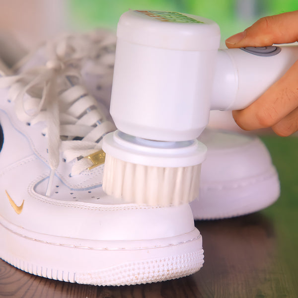 A close-up of someone using the Kleva Range Clean Sneaks Automatic Shoe Cleaner to restore a white sneaker with gold and black accents on a wooden surface. Make old shoes look new!.