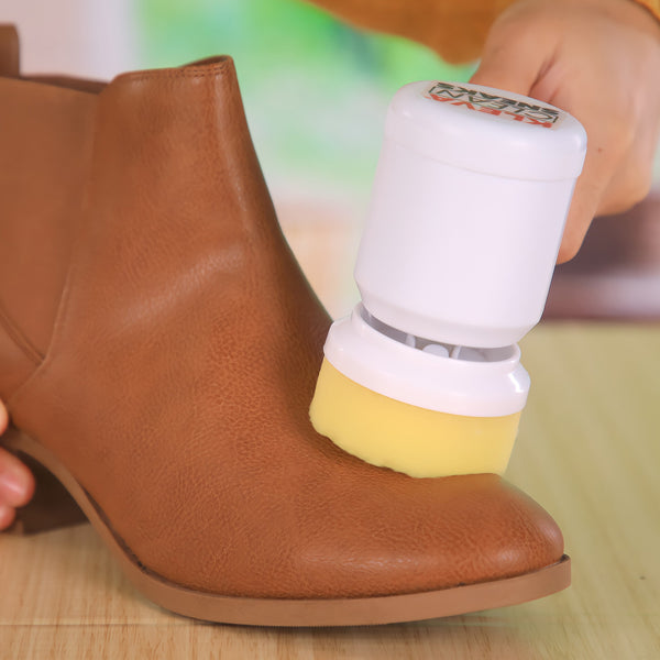 A person uses the Kleva Clean Sneaks Automatic Shoe Cleaner by Kleva Range on a brown leather boot, while the white and yellow device glides smoothly over a wooden surface. The softly blurred background highlights its effect.