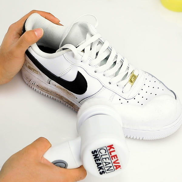 A pair of hands uses the Kleva Range Make old shoes look new! Kleva Clean Sneaks Automatic Shoe Cleaner on a white sneaker with a black Nike logo, easily removing visible dirt from the sole for impressive cleaning results.