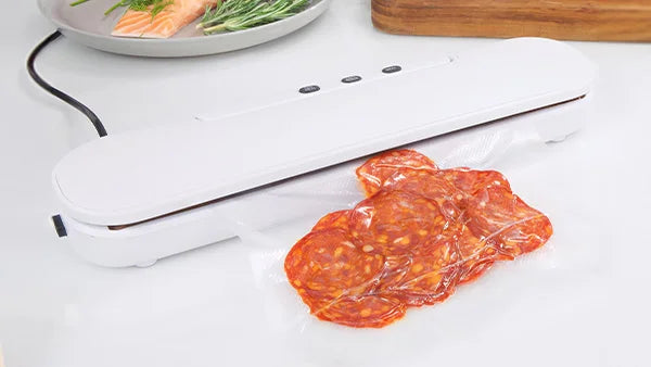 Kleva Vac Seal and Save machine vacuum sealing a bag of sliced salami on a white kitchen counter to preserve food freshness.