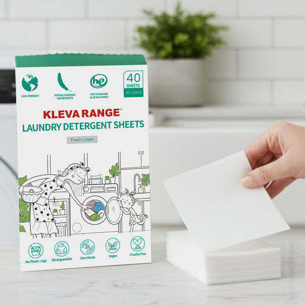 A hand holds a Stain Lifting Laundry Detergent Sheet (Fresh Linen, 40 Sheets) by Kleva Range above a counter next to its box—an eco-friendly, vegan, cruelty-free, hypoallergenic choice for plastic-free laundry.