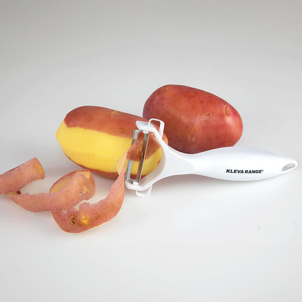 A z_archive_KlevaCut® Premium 3pc Knife Set from Kleva Range rests beside two red potatoes—one half-peeled with its skin and peelings scattered nearby—on a white surface.