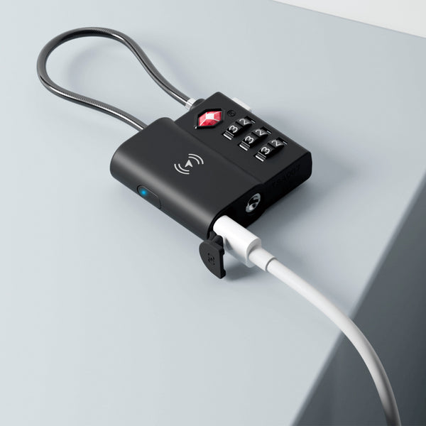 The Kleva TSA LockSmart Travel Tag Bluetooth Tracker by Kleva Range locks a device to a light gray surface, features a USB cable, wireless charging button, and works as an Apple Find My-compatible luggage tracker. Free travel tips ebook included.