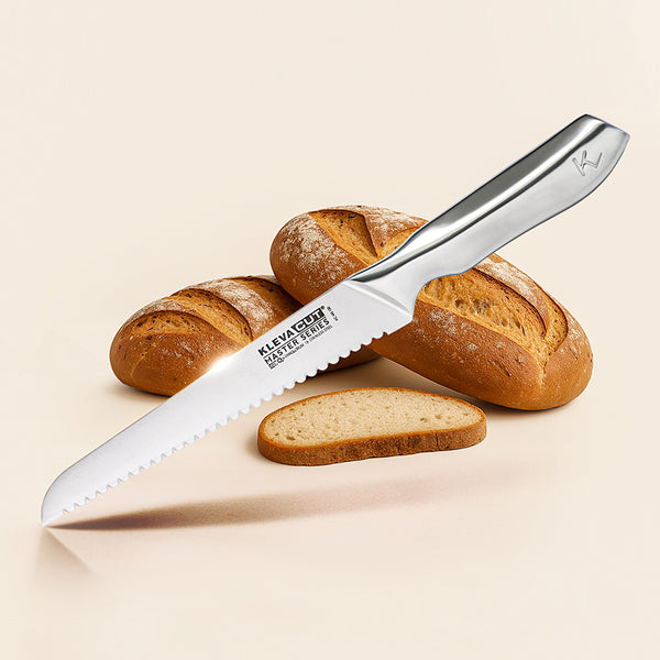 The Kleva Range KlevaCut® Master Series Double-Edge Serrated Bread Knife (20cm) with a stainless steel handle is displayed in front of two whole loaves and a bread slice on a neutral background.