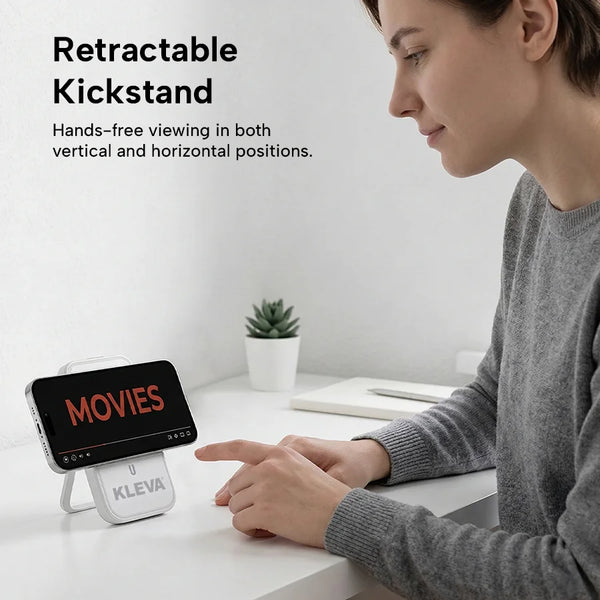 Person using a KLEVA phone stand with a smartphone displaying 'MOVIES' on a desk.