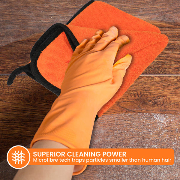 A hand in an orange glove wipes a wooden surface with The World's Best Cleaning Cloth by Kleva Range. Label reads: "SUPERIOR CLEANING POWER. Eco-friendly, reusable microfibre traps tiny particles.