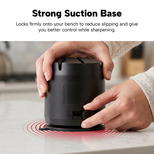 A person presses down on the KLEVA® ElectraSharp by Kleva Range, showing how its strong suction base locks firmly onto the countertop for slip-free electric knife sharpening. Red rings highlight the powerful suction feature.