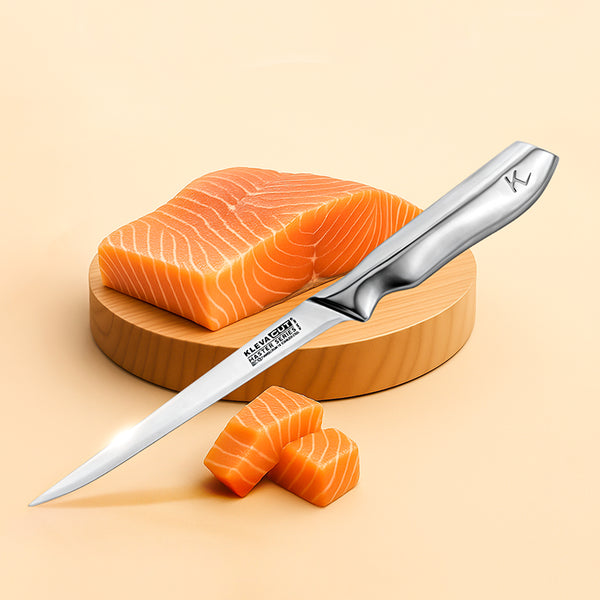 The Kleva Range KlevaCut® Master Series Professional Fillet Knife - 21cm, with a flexible stainless steel blade and engraved handle, lies on a round wooden board beside a large raw salmon piece and two salmon cubes.