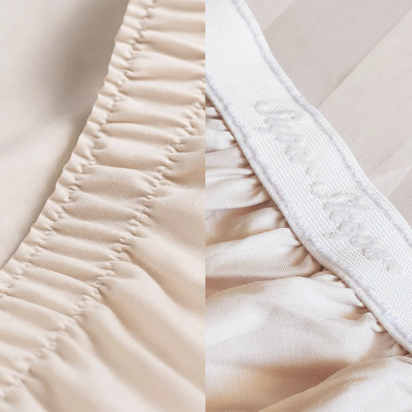 Close-up of two sheet corners: left has a plain elastic seam, right (from Super Sleeper Pro's Imperial Dream Sheets™ 4pc Bedding Set) features a white cursive label. Both are secure-fit, light beige 1200TC cotton sateen bedding.