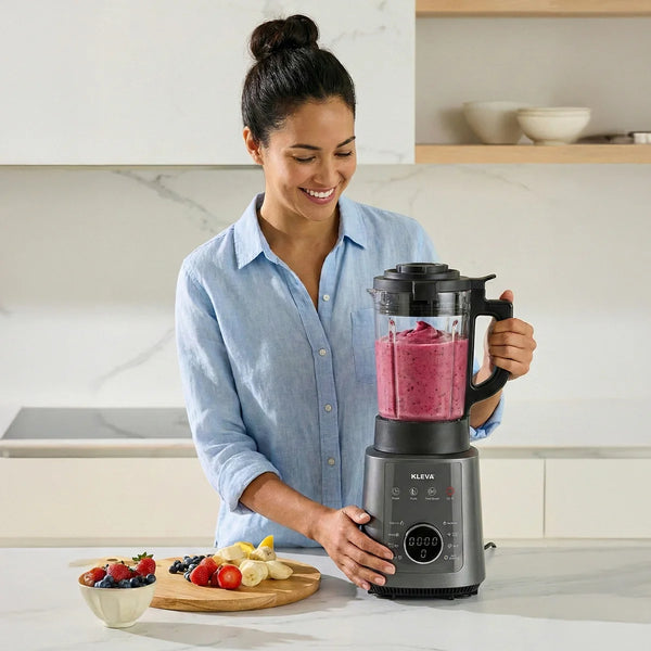 A woman smiling while using the Kleva Mealio high-speed blender to create a thick, nutritious berry smoothie.