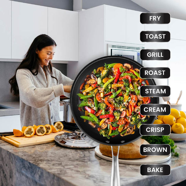 A woman cooks in a modern kitchen with the Kleva Range Perfect Pro Pan Premium Non-Stick 26cm Frying Pan and fresh veggies. A colorful stir-fry steams in the pan, while cooking methods are listed next to a FREE Universal Glass Lid with Timer.