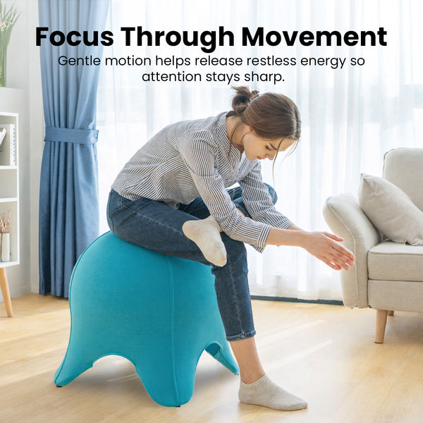 A woman leans forward while sitting on the KLEVA® Posture Chair by Kleva Range in a bright living room. Black text above reads, “Stay sharp—active sitting boosts posture, core strength & back support while you move.”.