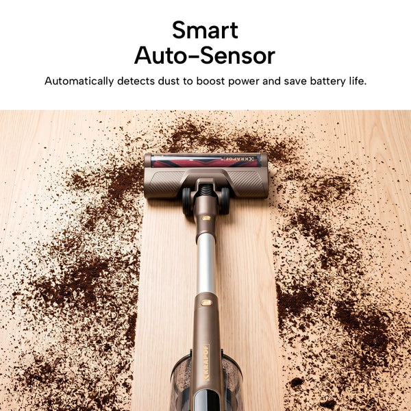 The KRAPOF® S3 Power Vac Cordless Stick Vacuum by Kleva Range is shown cleaning coffee grounds on a wooden floor, with its smart auto-sensor detecting dust and pet hair for efficient, battery-saving performance. Includes an extra FREE second battery.