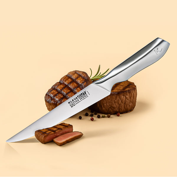 A Kleva Range KlevaCut® Master Series Professional Slicer Knife - 20cm with Japanese steel blade rests beside two grilled steaks, one topped with rosemary. Sliced steak and peppercorns are scattered on a beige background.