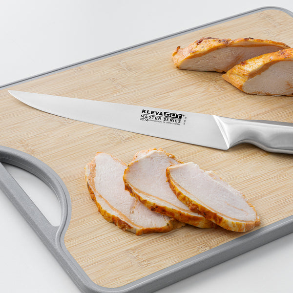 A Kleva Range KlevaCut® Master Series Professional Slicer Knife - 20cm, made from premium Japanese steel, sits on a light wooden cutting board next to neatly sliced pieces of cooked chicken breast.