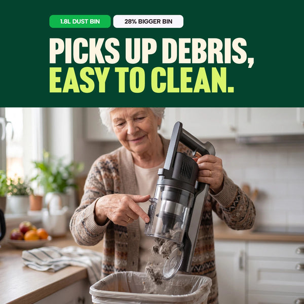 An older woman empties the KRAPOF® Power Vac S3 Cordless Stick Vacuum by Kleva Range into a kitchen trash bin. Text above highlights its 1.8L dust bin—28% larger for fewer trips to the bin, powerful debris pickup, and easy-clean design, making it perfect for efficient pet hair removal and tackling daily messes. Plus, it comes with an extra FREE second battery for uninterrupted cleaning.