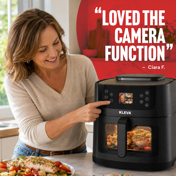 A woman stands in a kitchen, smiling as she presses a button on the black Kleva Range KLEVA® SteamCrisp IQ Steam Air Fryer with AI Food Detection Camera 8L, watching food cook inside the steam-assisted air fryer. A testimonial reads, “Loved the camera function – Ciara F.”.