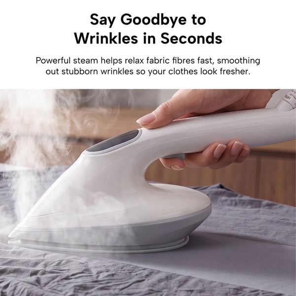 A person uses the KLEVA® Crease Boss Steam Iron by Kleva Range on a gray shirt. Visible steam rises from the device as it effortlessly removes wrinkles and smooths the fabric. Text above highlights fast wrinkle reduction for quick and effective garment care.