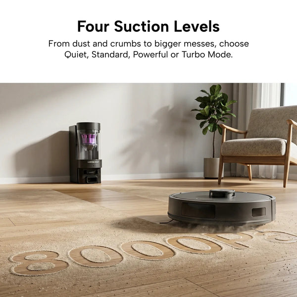 The KRAPOF® Self Empty Robo VacIQ Robot Vacuum and Mop by Kleva Range cleans a wooden floor with "8000Pa" in dust, showcasing four suction levels. Its self-emptying base is nearby, with a chair and plant in the background.