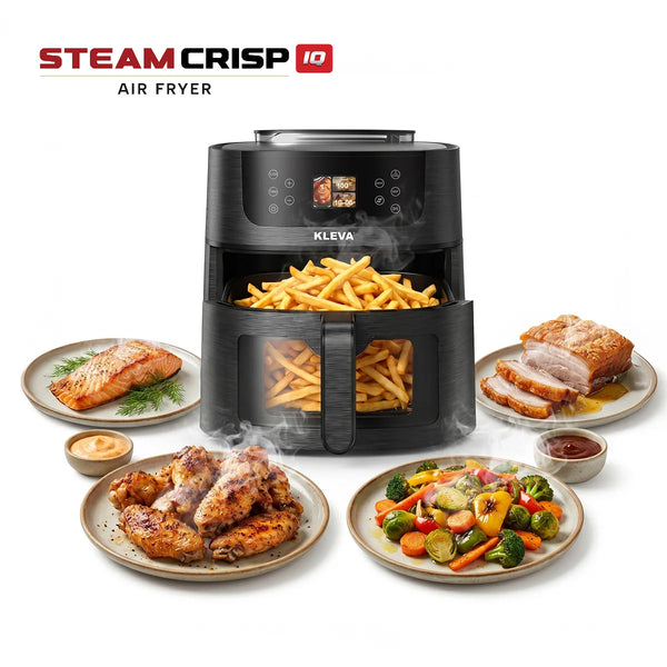 A black KLEVA® SteamCrisp IQ Steam Air Fryer with Smart Food Detection 8L from Kleva Range, filled with French fries, sits amid plates of cooked salmon, chicken drumsticks, roast pork, vegetables and dipping sauce. Steam rises from the food.