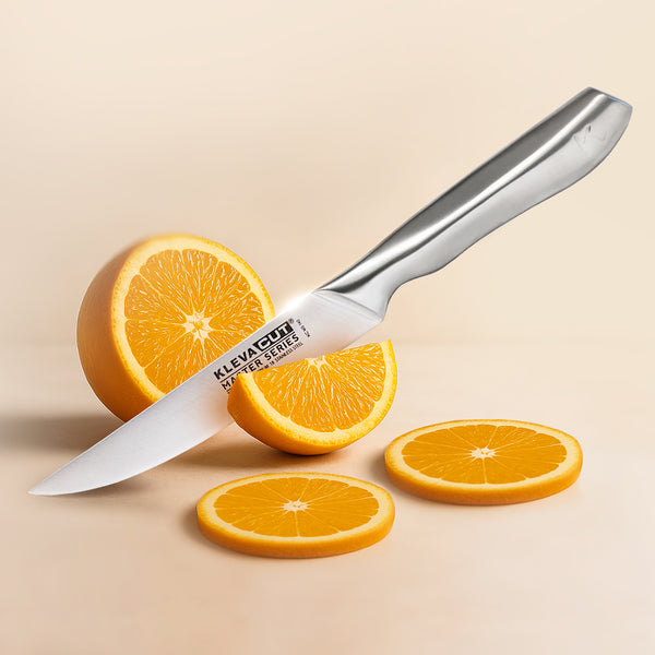 The KlevaCut® Master Series Professional Utility Knife - 11.5cm by Kleva Range, crafted from Japanese stainless steel, is placed beside a halved orange and three orange slices on a beige surface. The blade bears the Kleva Range name.