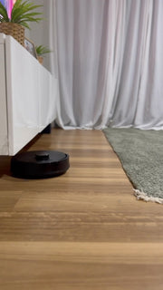 The robot sliding under a low TV unit onto a timber floor.